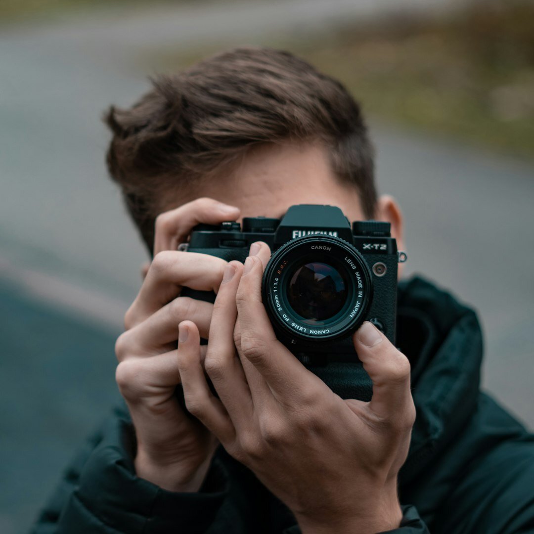 Professional headshot of a male photojournalism instructor holding a camera