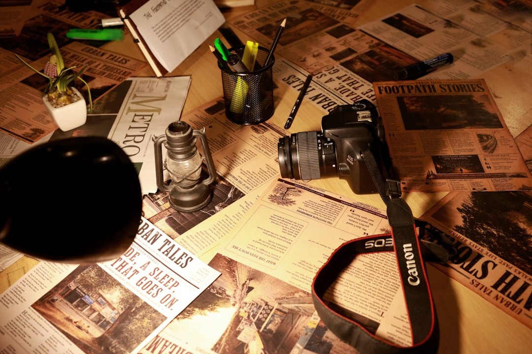 Overhead view of a newsroom desk with a camera, laptop and press notes